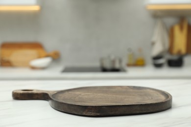 Photo of Wooden cutting board on white table in kitchen, closeup. Space for text