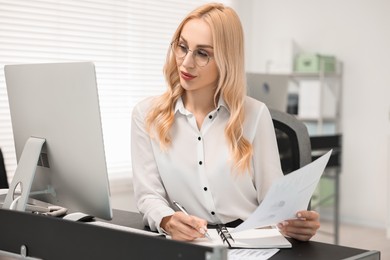 Secretary working with document at table in office