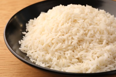 Photo of Plate with delicious rice on wooden table, closeup