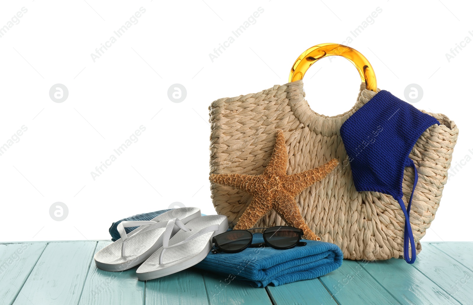 Photo of Stylish bag with beach accessories on light blue wooden table