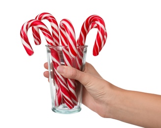 Photo of Woman holding glass with sweet Christmas candy canes on white background, closeup