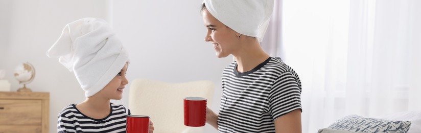 Image of Mother and her little daughter with cups spending time together at home, banner design