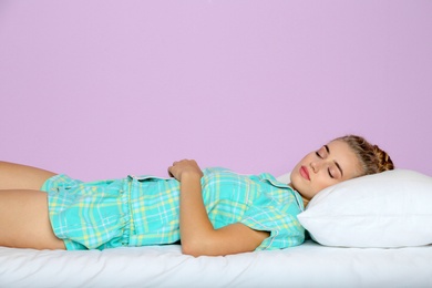 Beautiful woman sleeping with comfortable pillow on bed against color background