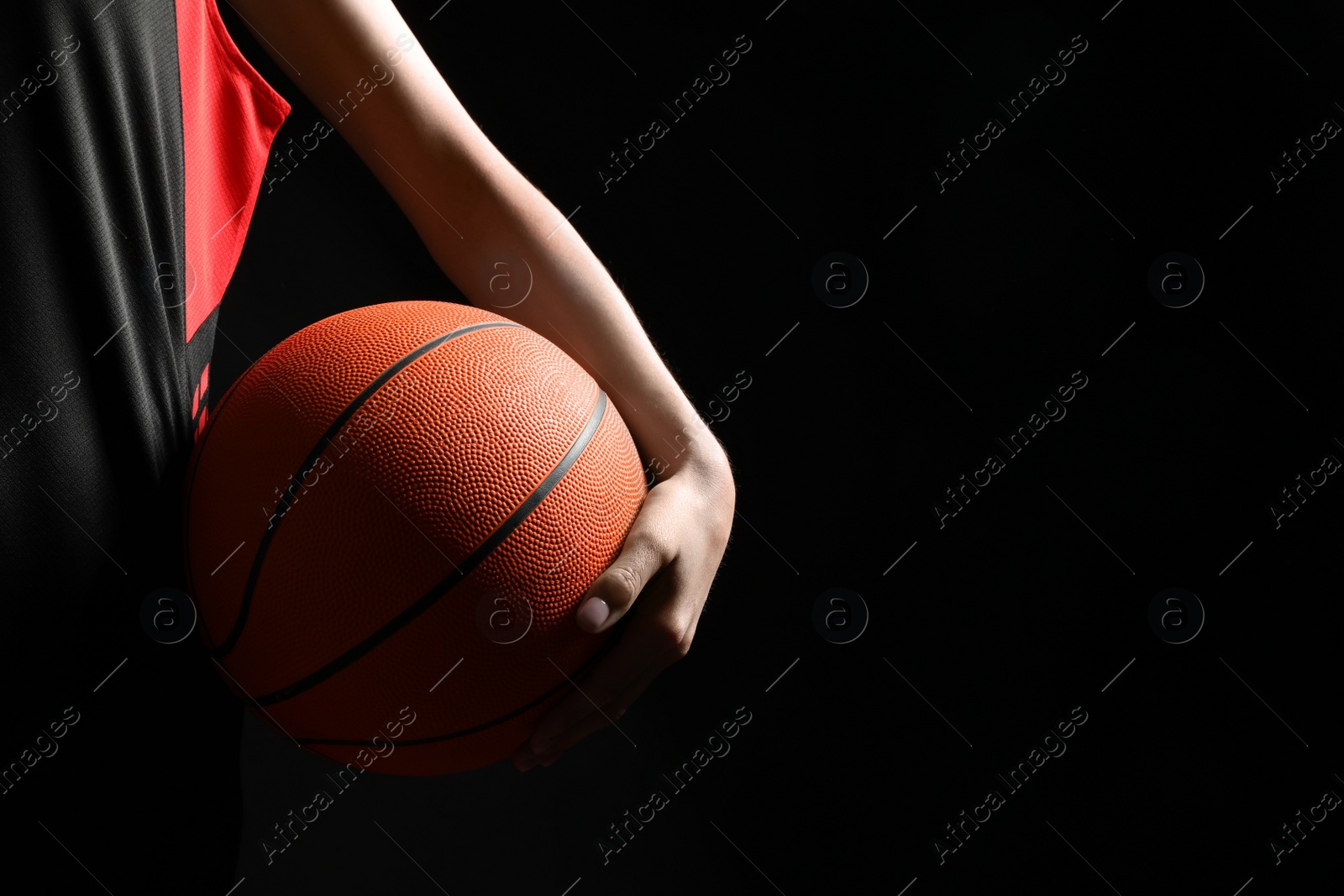 Photo of Basketball player with ball on black background, closeup. Space for text