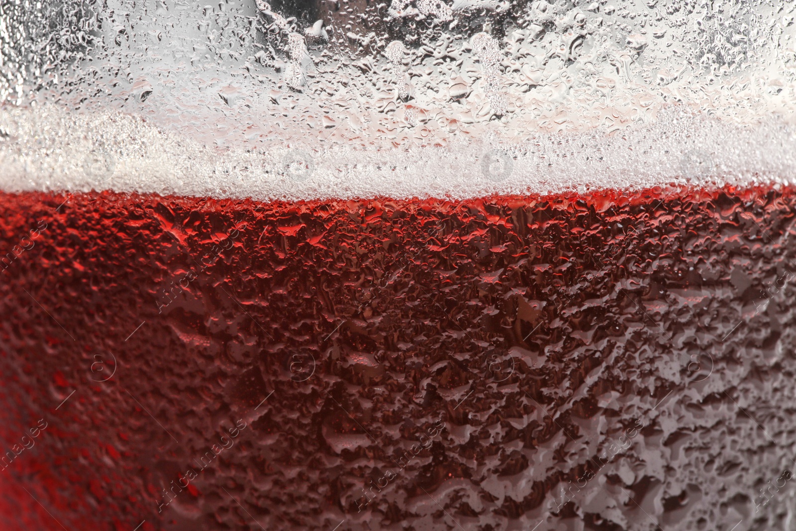 Photo of Glass of tasty red beer with foam, closeup