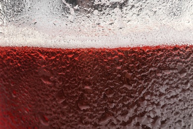 Photo of Glass of tasty red beer with foam, closeup