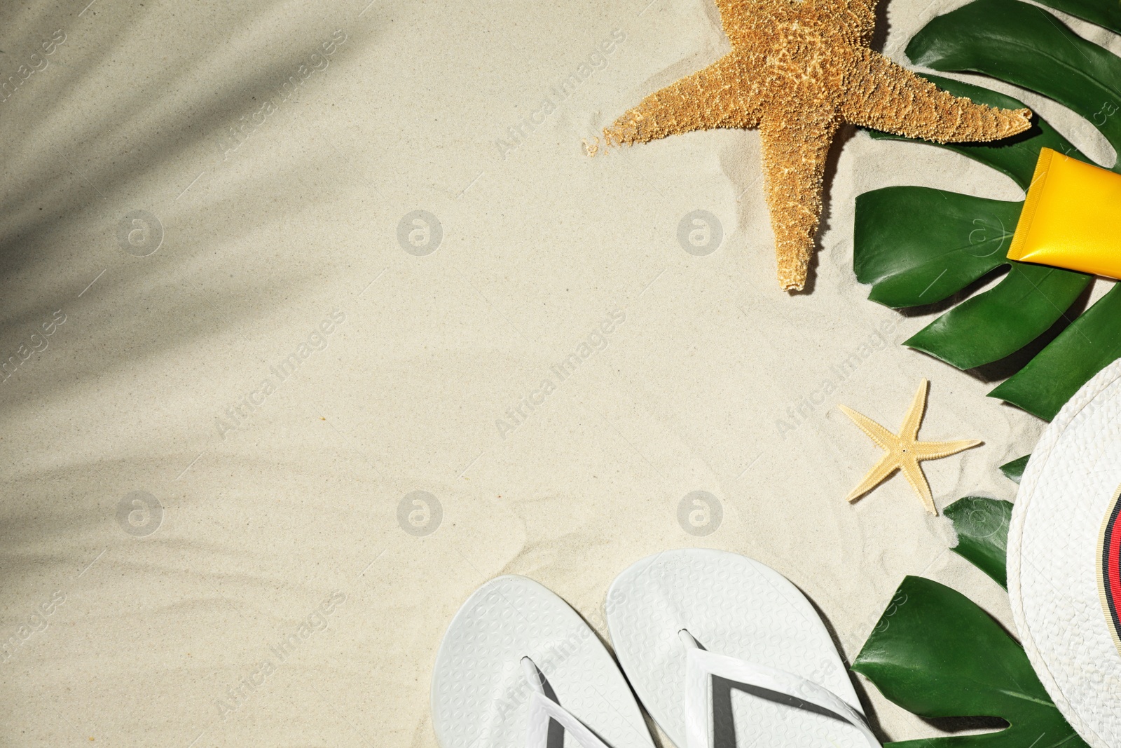 Photo of Composition with beach accessories and space for text on sand, flat lay