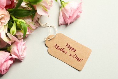 Image of Happy Mother's Day greeting label and beautiful flowers on beige background