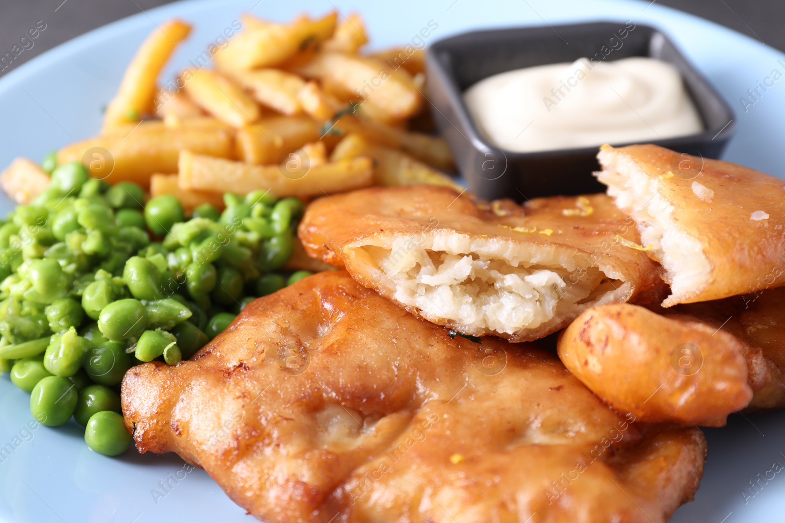 Photo of Tasty fish, chips, sauce and peas on table, closeup