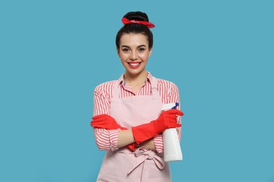 Photo of Young housewife with detergent on light blue background