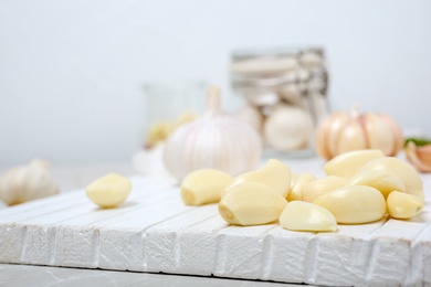 Photo of Ripe garlic cloves on wooden board, closeup