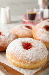 Photo of Delicious donuts with jam and powdered sugar on wooden board, closeup