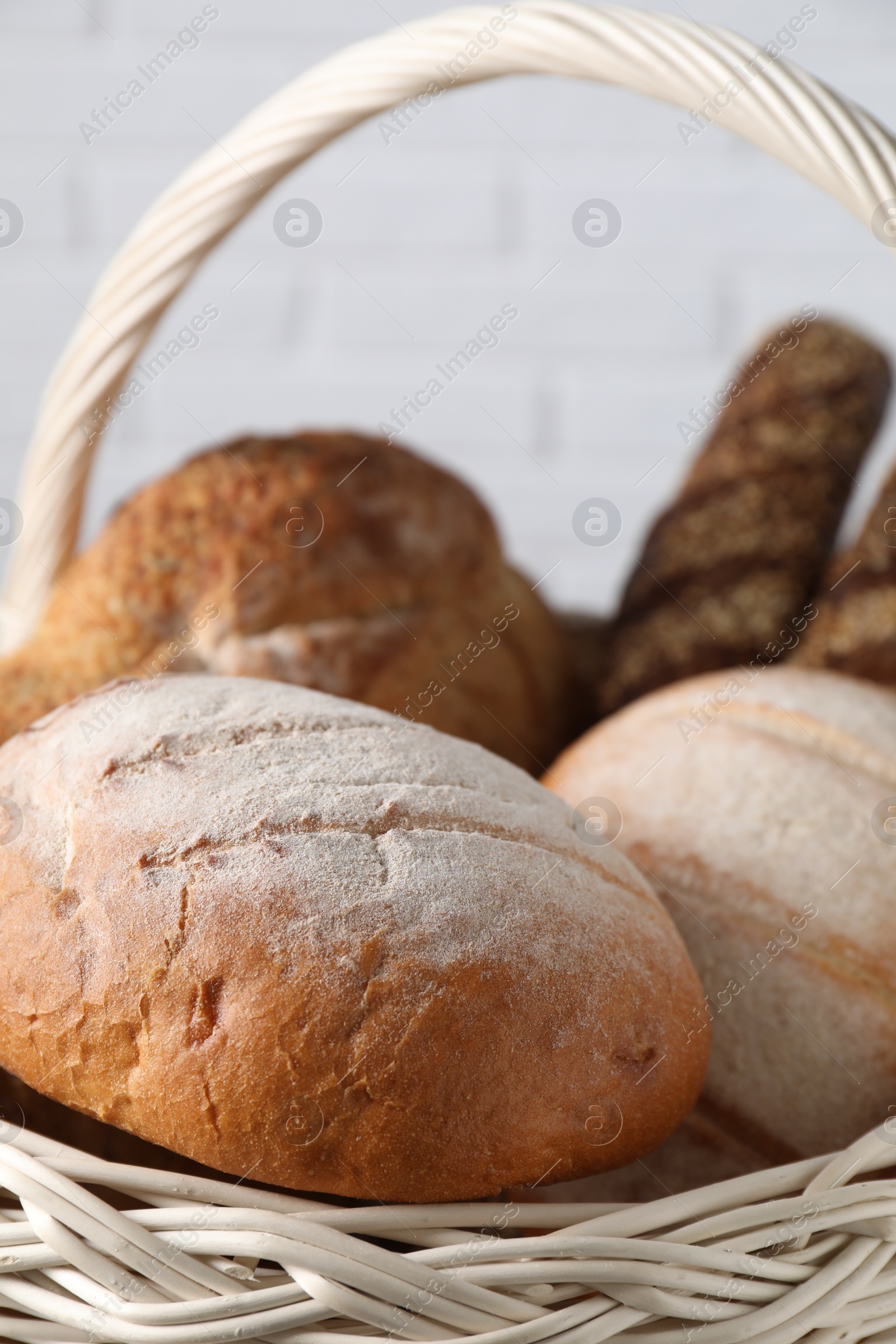Photo of Different types of bread in wicker basket, closeup