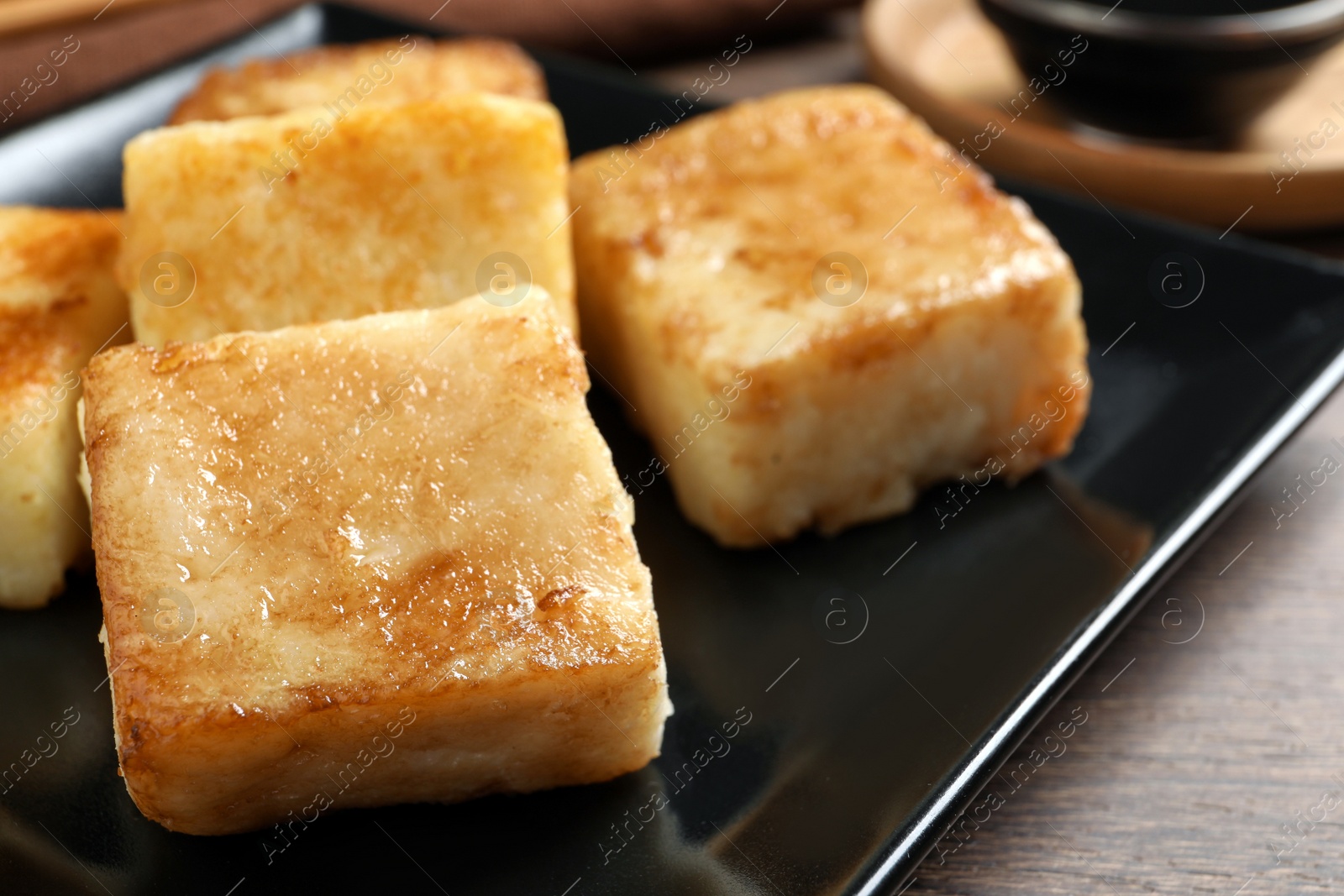 Photo of Delicious turnip cake on ceramic black plate, closeup