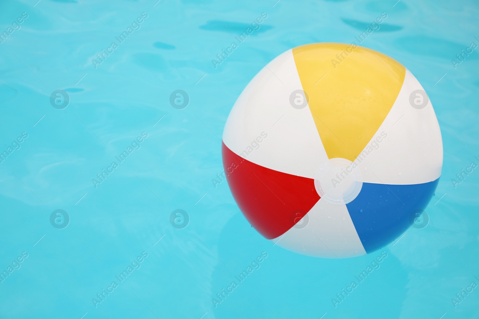 Photo of Inflatable colorful beach ball floating on water in swimming pool, space for text