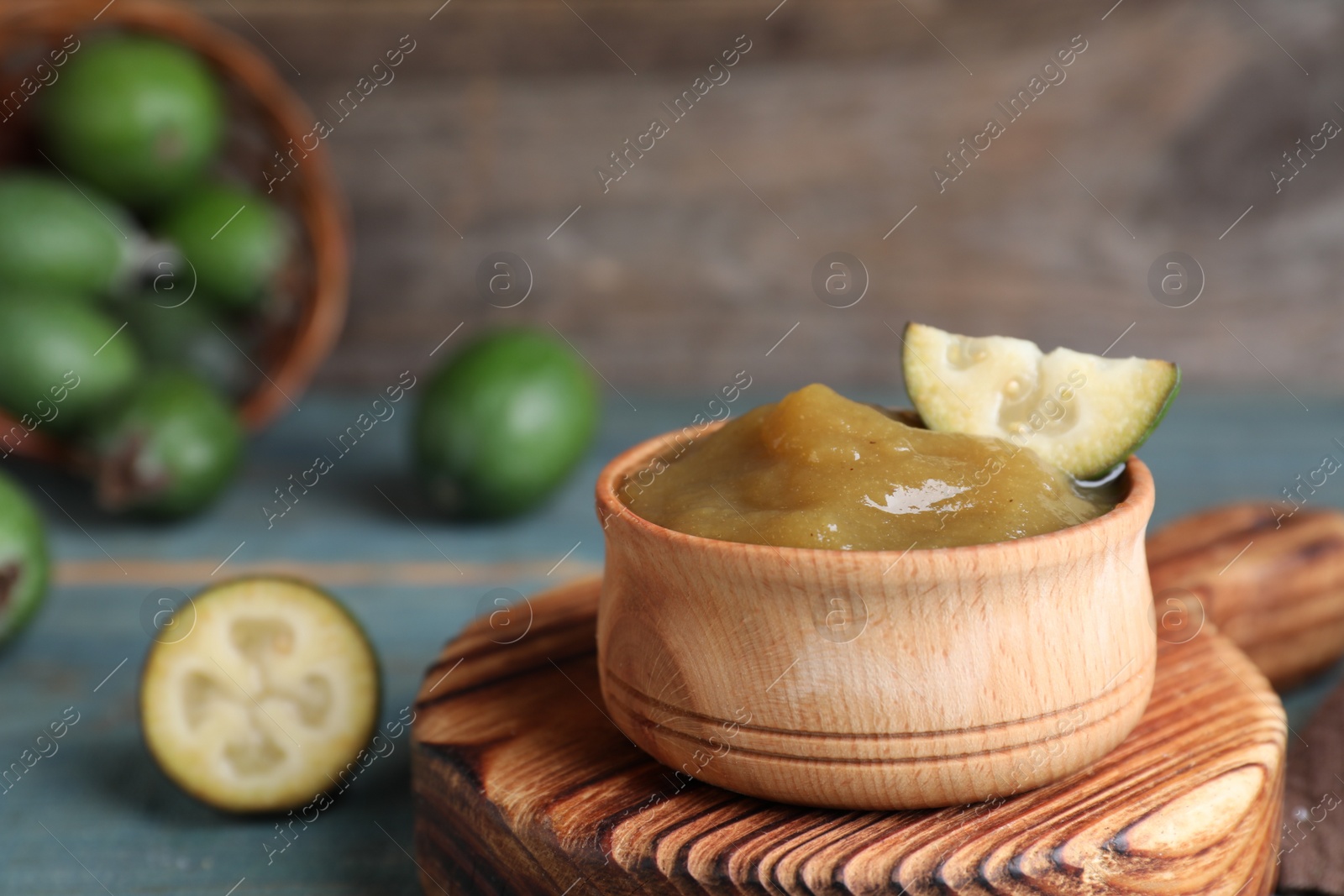 Photo of Feijoa jam and fresh fruit on wooden board, closeup. Space for text