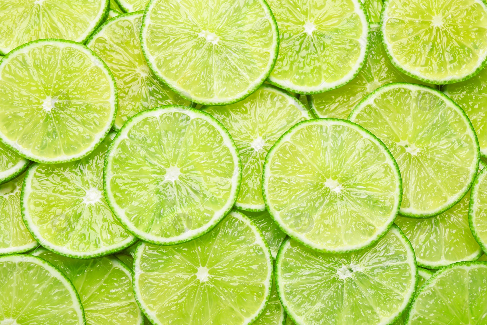Photo of Many fresh juicy lime slices as background, top view