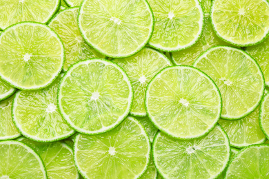 Many fresh juicy lime slices as background, top view