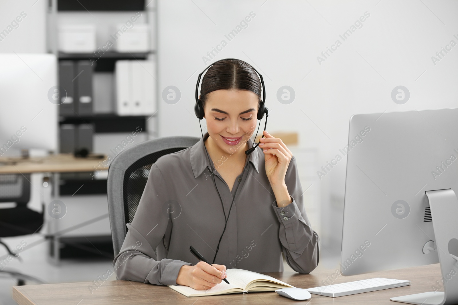 Photo of Hotline operator with headset and notebook working in office