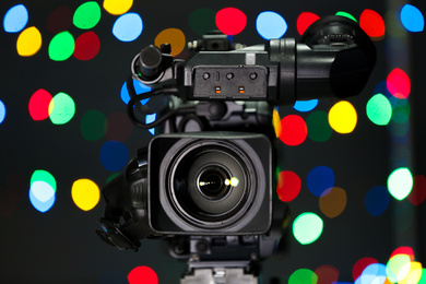 Photo of Modern video camera against blurred colorful lights