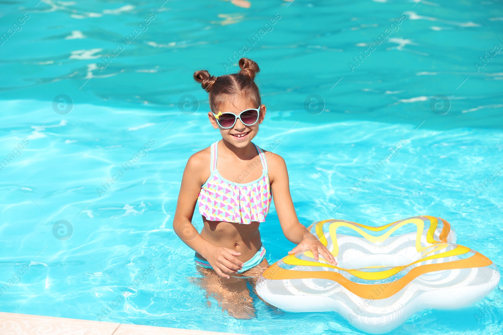 Photo of Cute little girl with inflatable ring in swimming pool