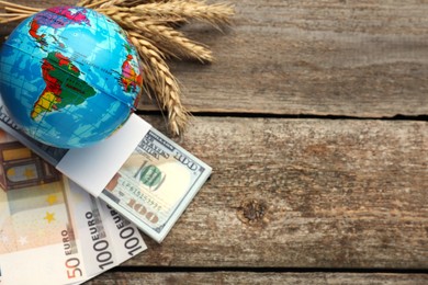 Photo of Globe, ears of wheat and banknotes on wooden table, flat lay with space for text. Import and export concept