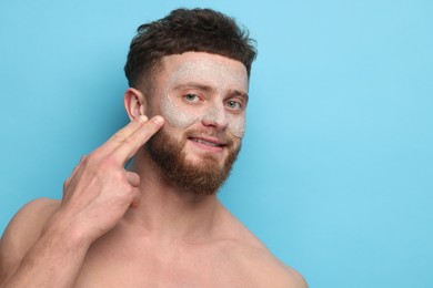 Photo of Handsome man with facial mask on his face against light blue background, space for text