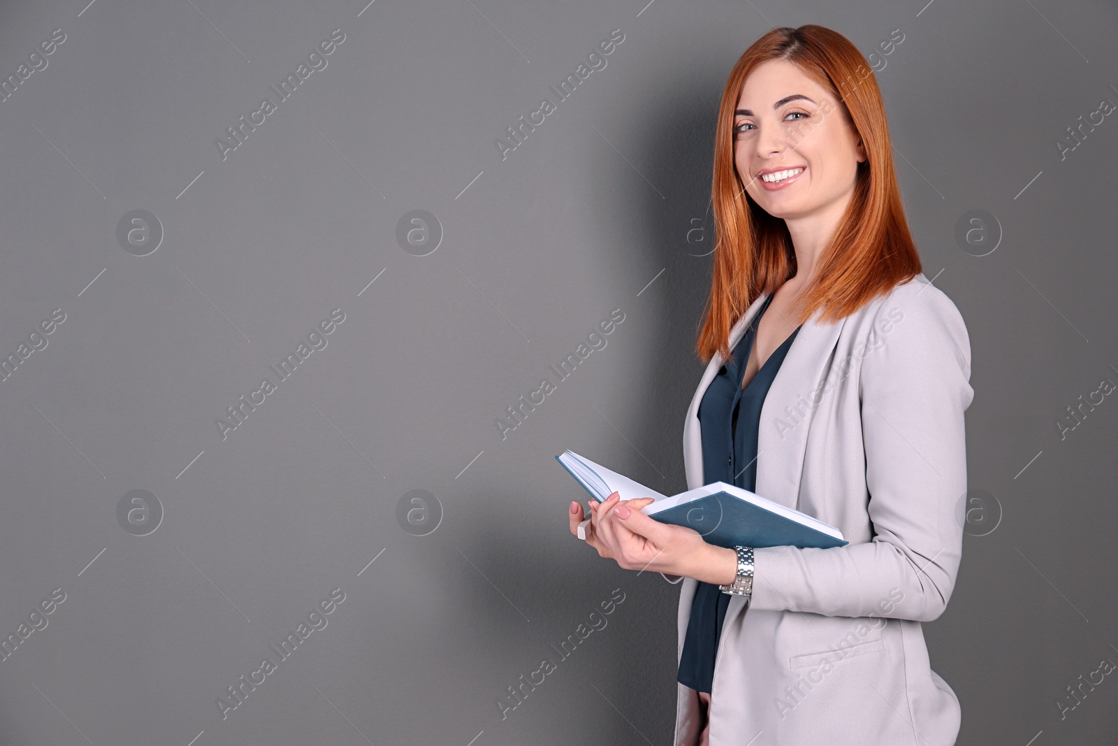 Photo of Beautiful young teacher with book on grey background