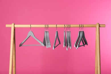 Photo of Wooden rack with clothes hangers on color background