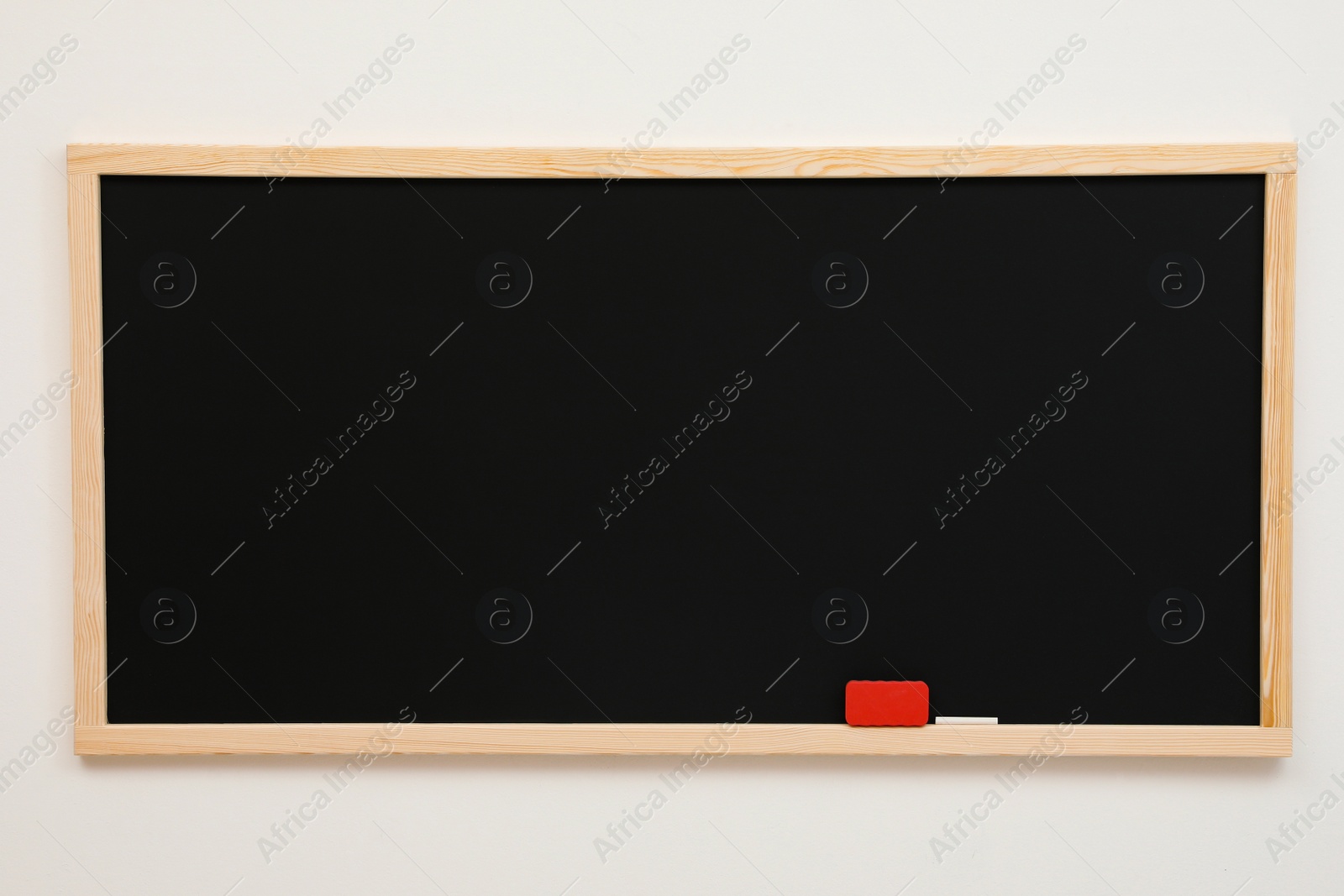 Photo of Clean black chalkboard hanging on white wall