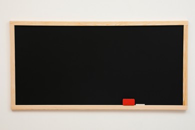 Clean black chalkboard hanging on white wall