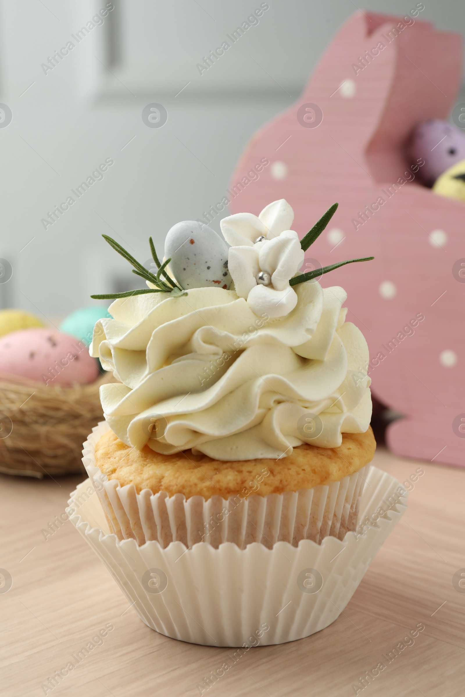 Photo of Tasty Easter cupcake with vanilla cream on wooden table