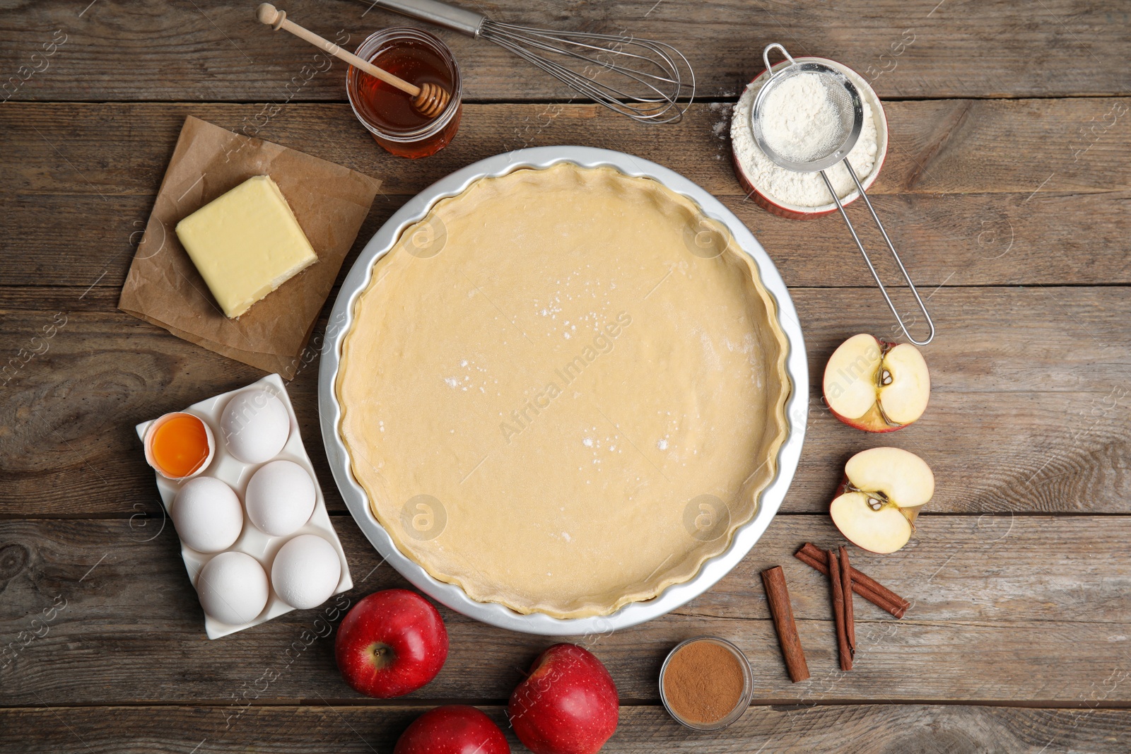 Photo of Raw dough and ingredients for traditional English apple pie on wooden table, flat lay