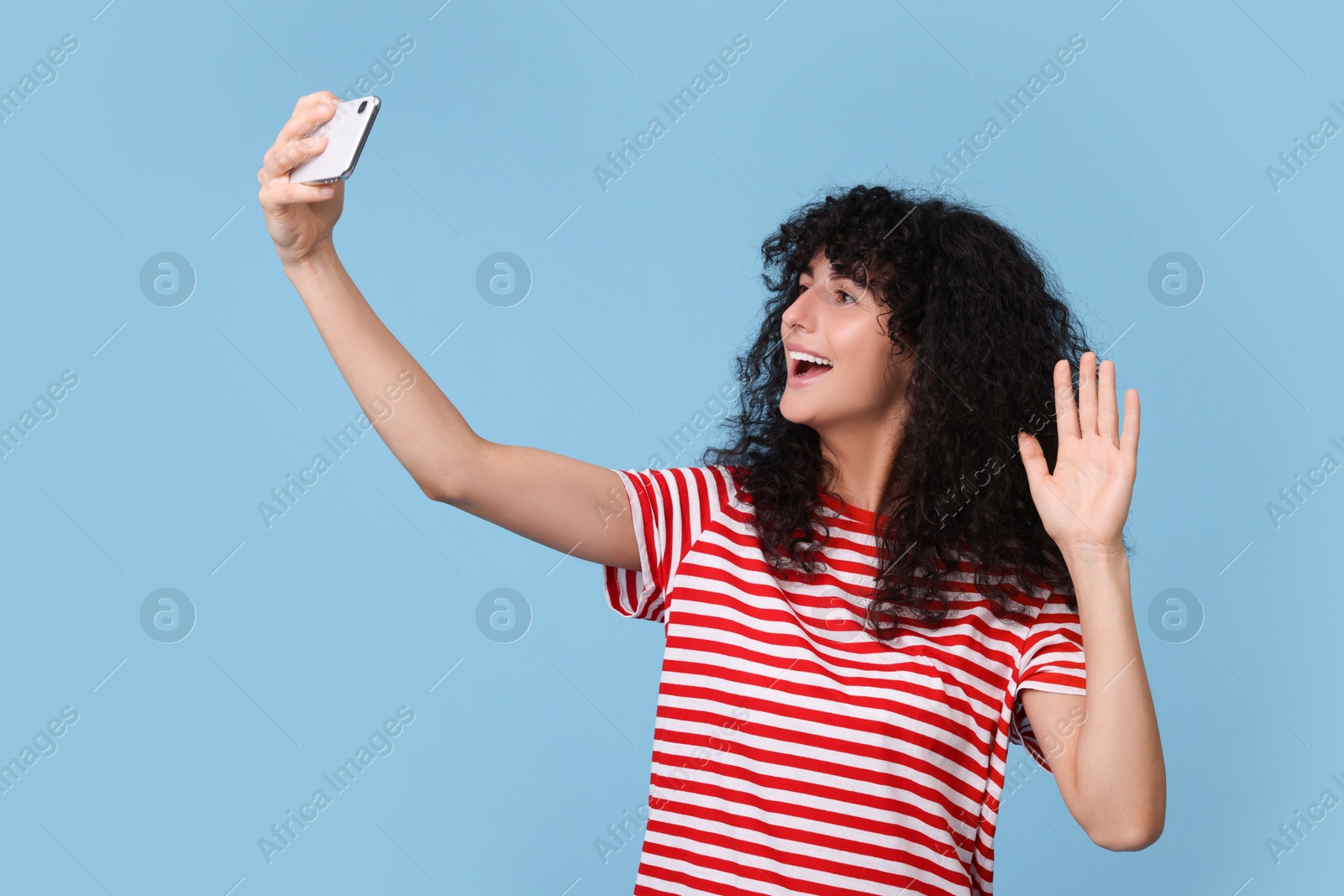 Photo of Beautiful young woman taking selfie on light blue background