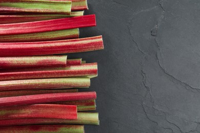 Photo of Fresh ripe rhubarb stalks on grey textured table, top view. Space for text