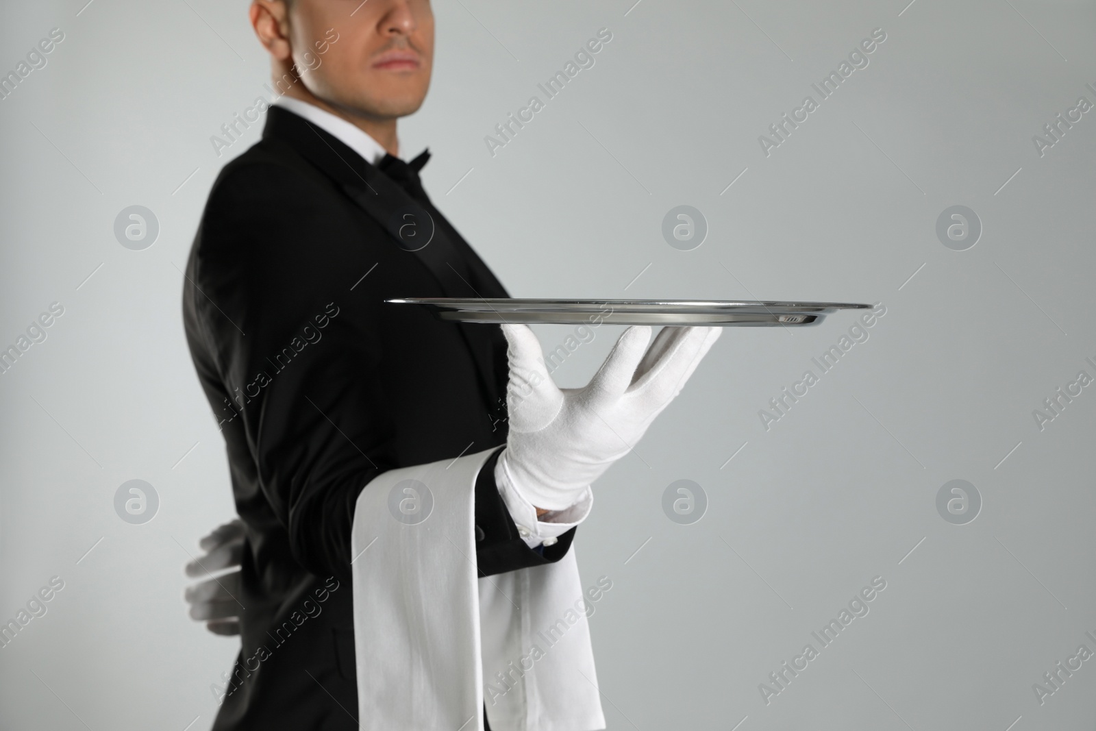 Photo of Butler with tray on light grey background, closeup