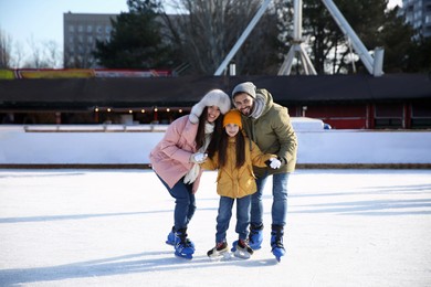 Image of Happy family spending time together at outdoor ice skating rink