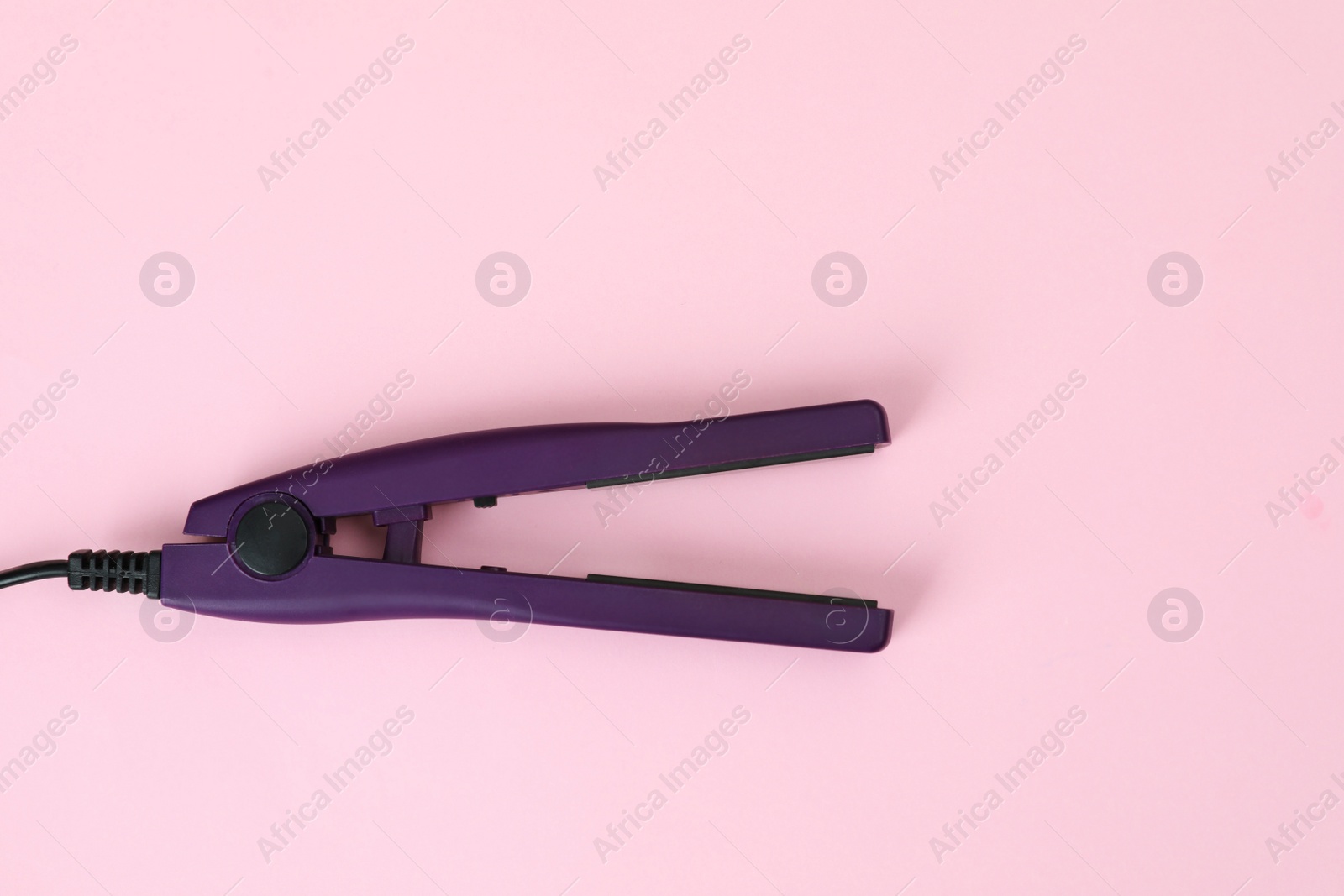 Photo of Modern hair iron for straightening on color background, top view