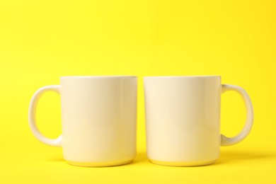 Photo of Two white ceramic mugs on yellow background