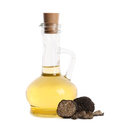 Glass jug of oil and fresh truffles on white background