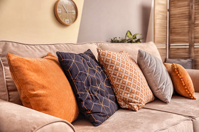 Image of Cushions with pattern, grey and orange on sofa indoors, closeup