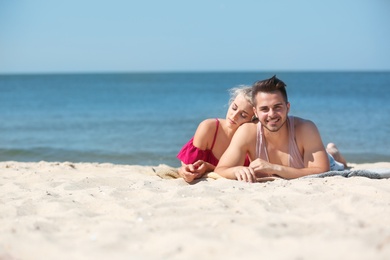 Photo of Happy young couple lying together at beach on sunny day