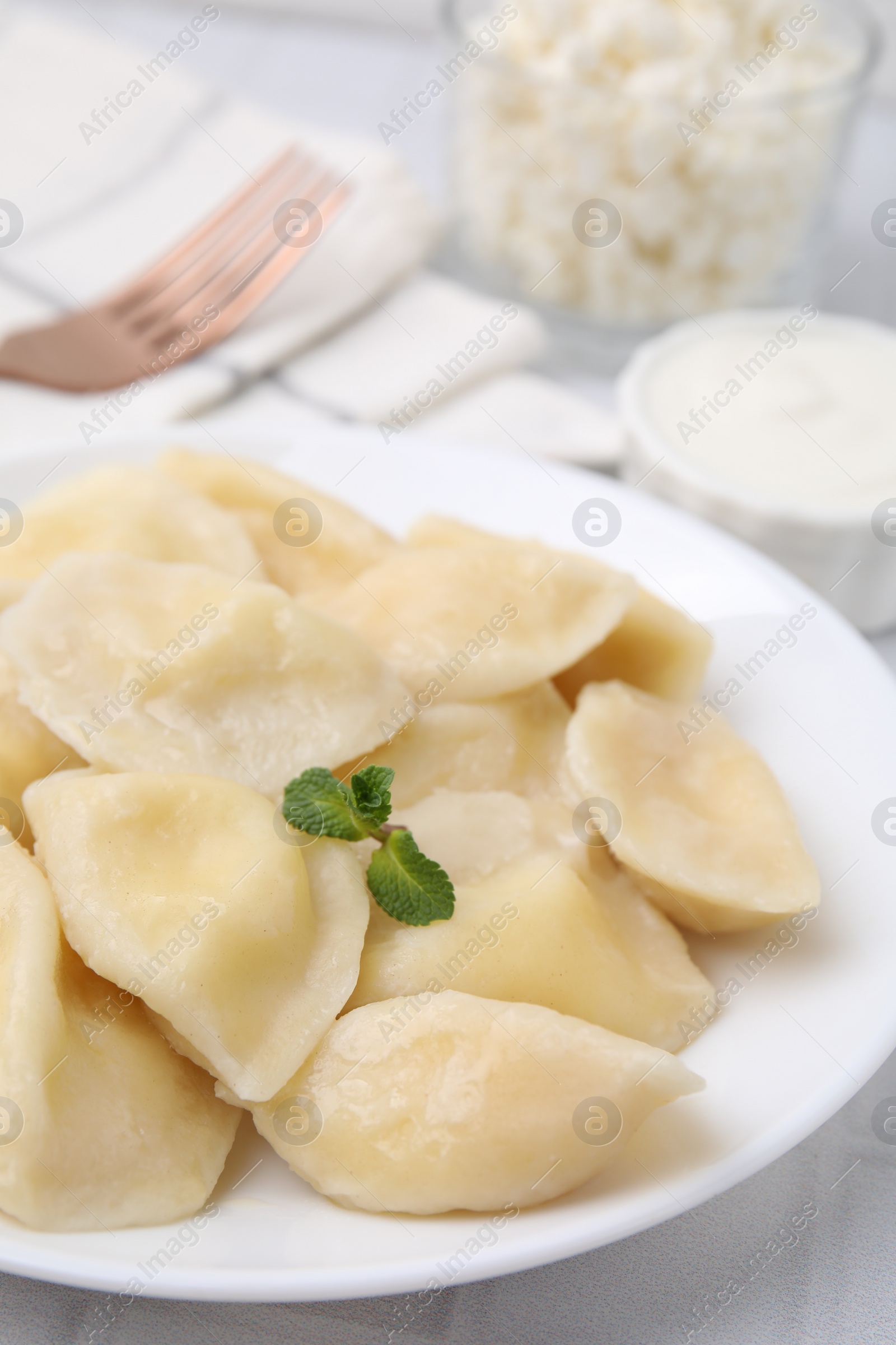 Photo of Plate of delicious dumplings (varenyky) with cottage cheese on table, closeup