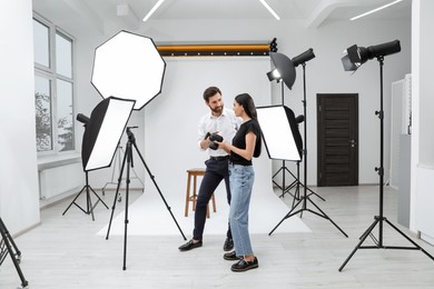 Professional photographer and model looking at pictures on camera in modern studio
