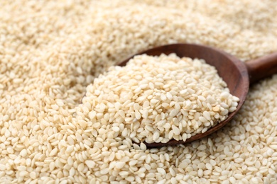 Photo of Wooden spoon on pile of white sesame seeds, closeup