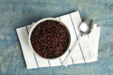 Photo of Flat lay composition with delicious cooked brown rice on color wooden table