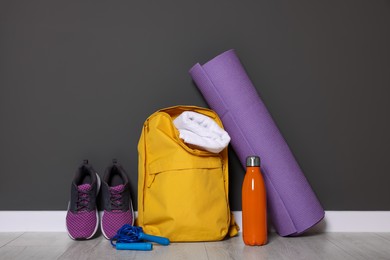 Photo of Backpack and sports equipment on floor near gray wall