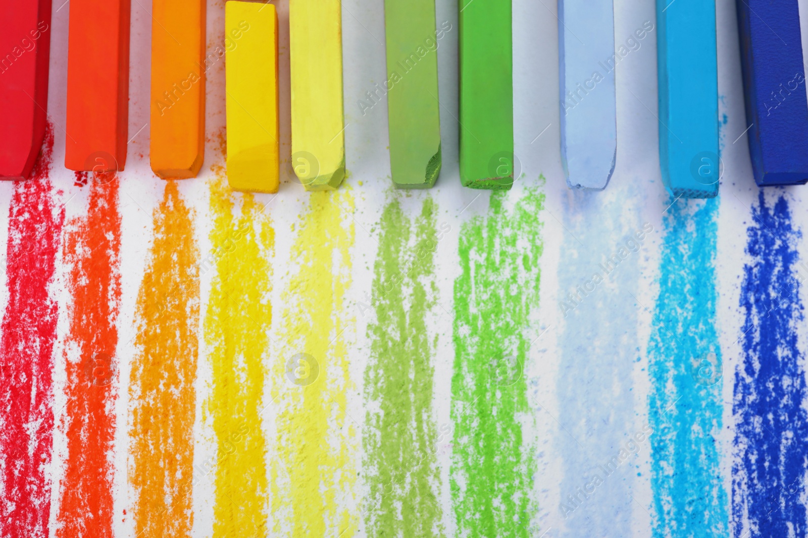 Photo of Colorful pastel chalks on white background, flat lay. Drawing materials