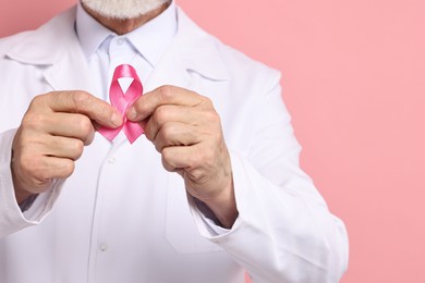 Photo of Mammologist with pink ribbon on color background, closeup and space for text. Breast cancer awareness