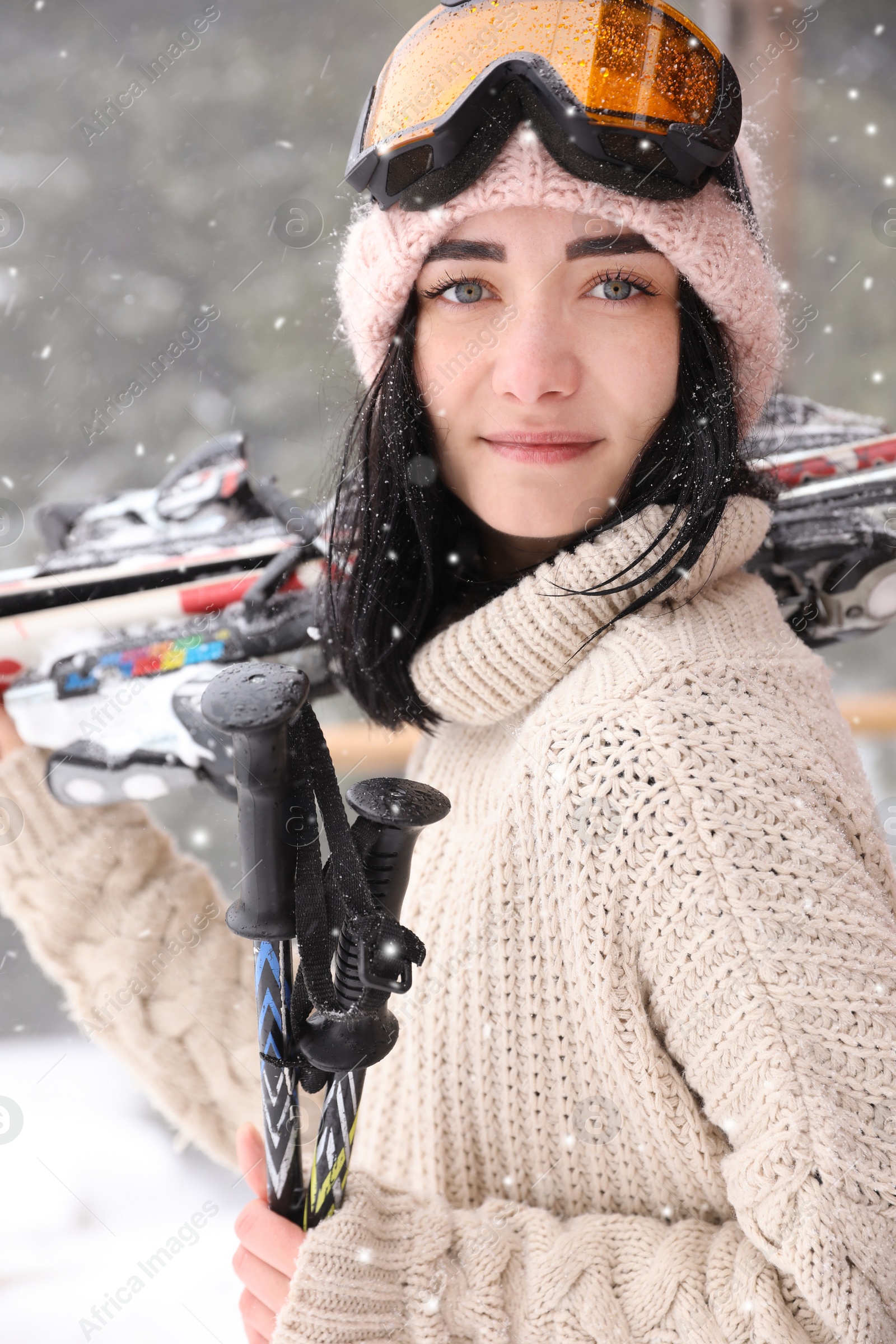 Photo of Young woman with skis wearing winter sport clothes and goggles outdoors